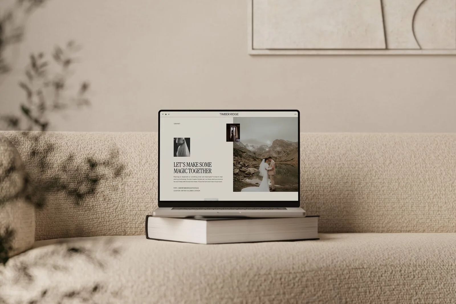 Laptop on stacked books on a cream sofa in a soft beige room.