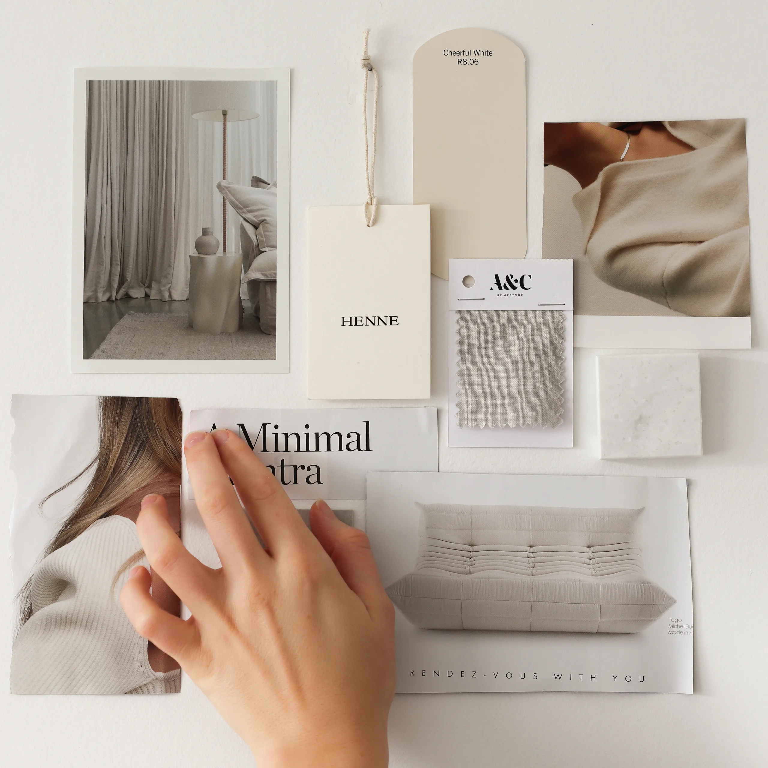 Hand arranging a beige brand mood board with photos, swatches, and typography samples.
