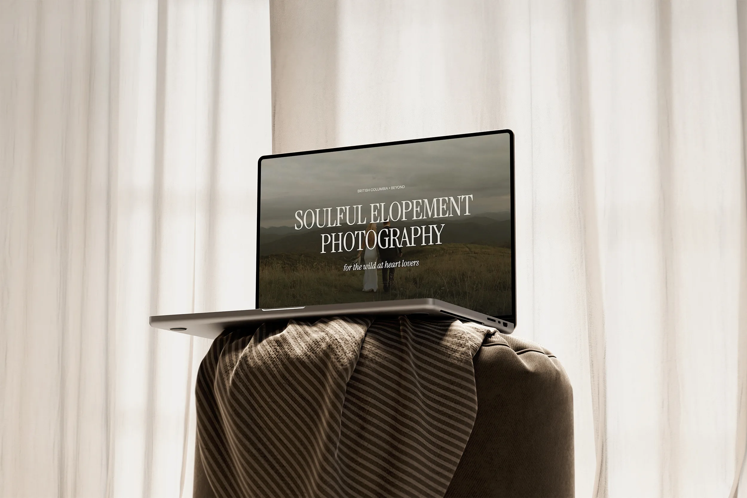 Laptop on a draped chair displaying “Soulful Elopement Photography.”